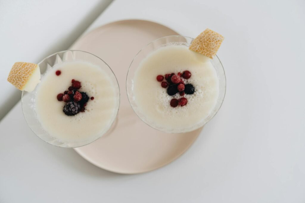 Berry smoothie next to frozen berries and lemon wedges